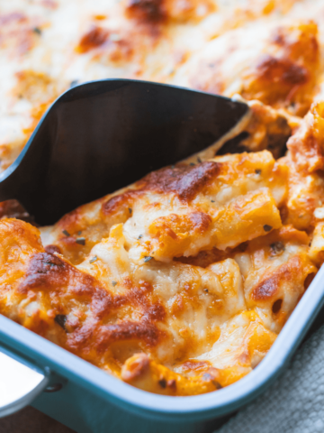 Saucy and cheesy baked ziti is topped with golden brown cheese in a casserole dish.