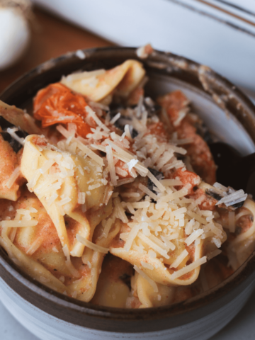 Bowl of Boursin and Tomato Pasta is topped with shredded parmesan cheese.