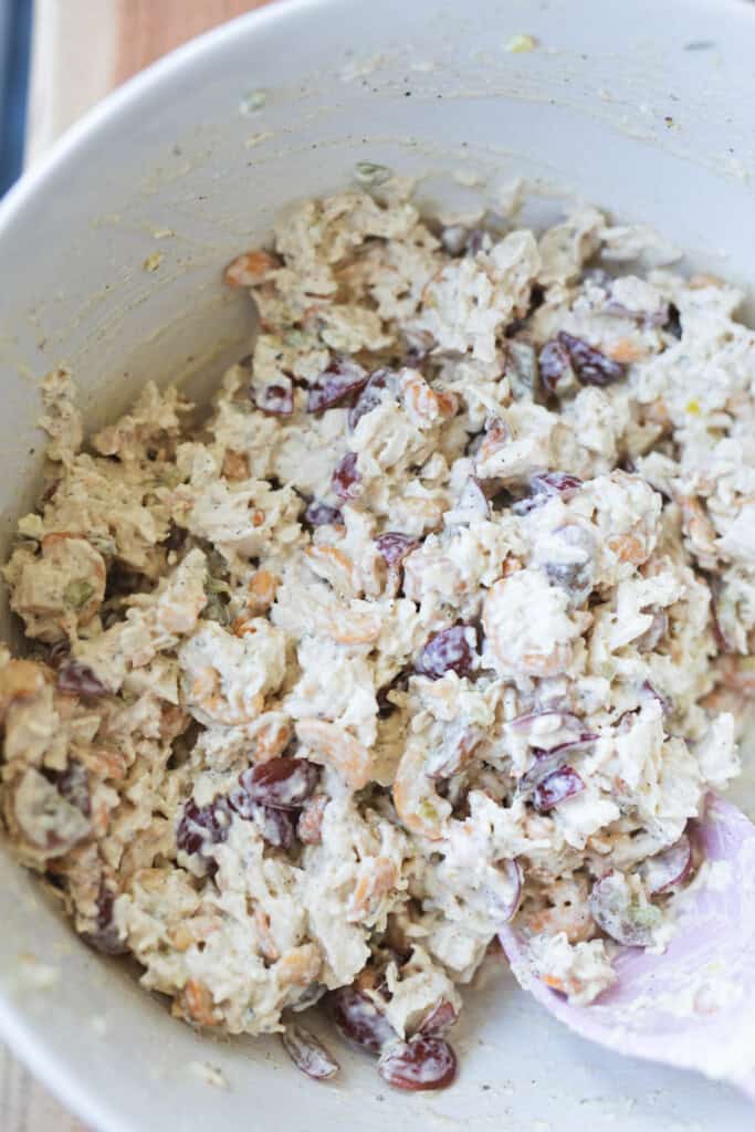 Prepared chicken salad sits in a large white mixing bowl.