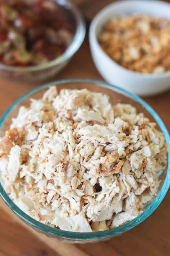 Shredded chicken sits prepared in a glass bowl.