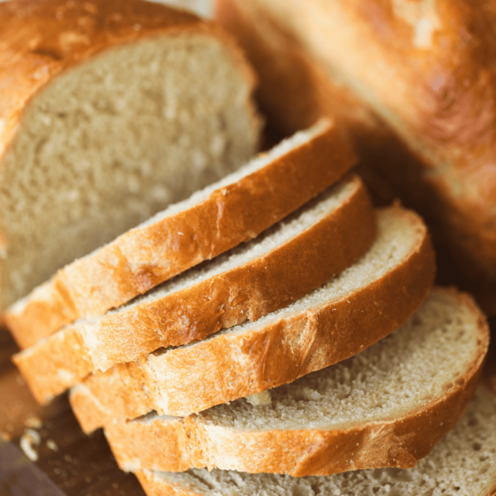 5 Ingredient Bread is cut into slices and sit on a wooden cutting board.