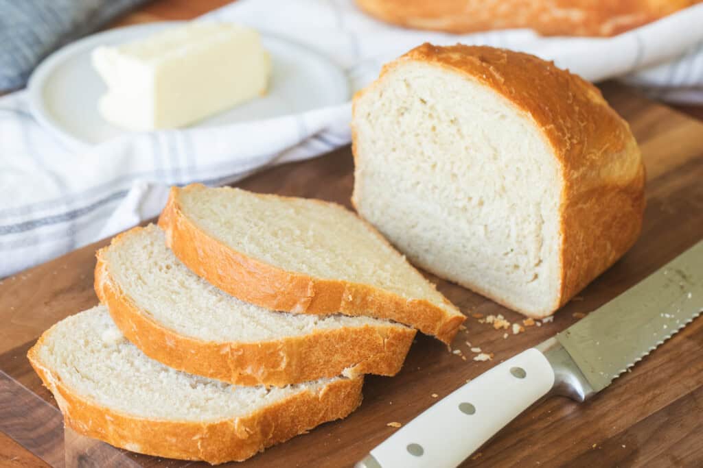 Three slices of 5 ingredient sandwich bread sit on a cutting board with a knife.