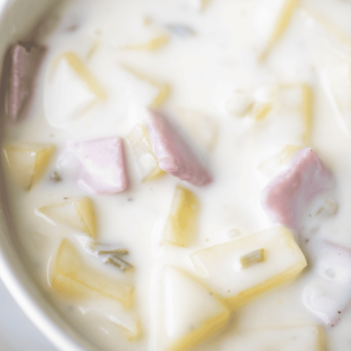 Tender potatoes and chunks of savory ham sit in a creamy white soup broth.