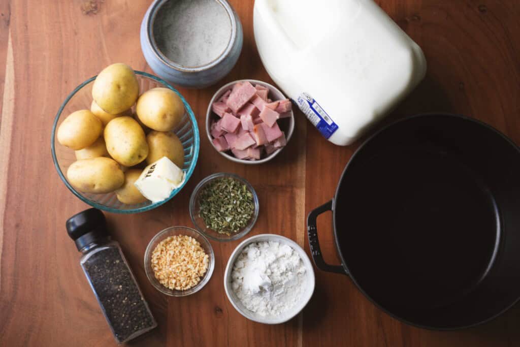 Ingredients for soup sit on wooden counter ready for cooking.