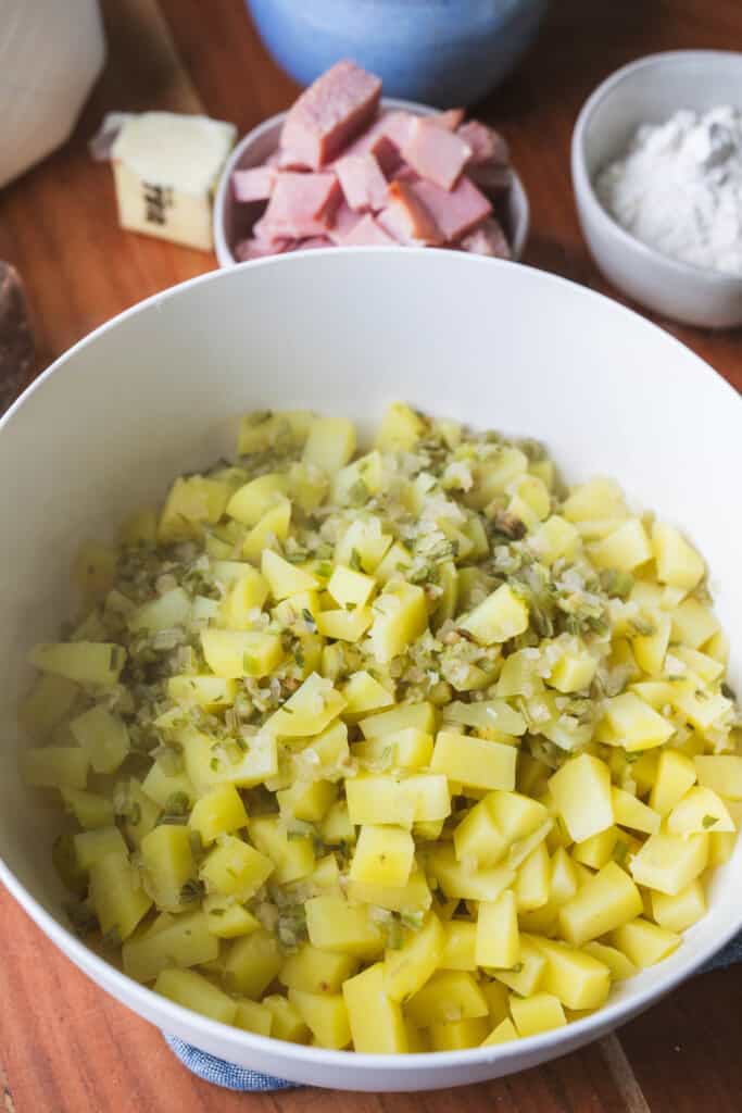 Cooked potatoes sit in a large white bowl.