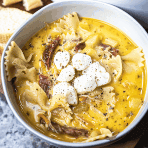 Bowl of creamy white lasagna soup is topped with mozzarella pearls and served up for eating.