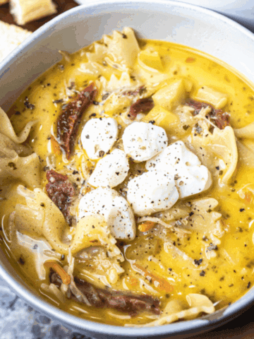 Bowl of creamy white lasagna soup is topped with mozzarella pearls and served up for eating.
