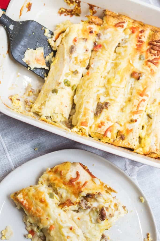 A black spatula serves up a breakfast enchilada on a plate.