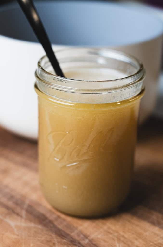 A glass mason jar is filled with warm breakfast topping ready for serving.